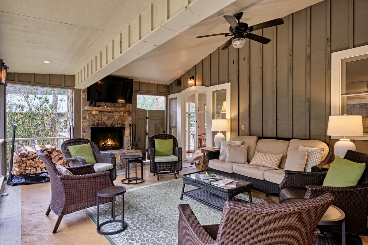 A comfortable living area anchored by a central fireplace (not operational), plush seating, a coffee table, and a television. Natural light pours in through the windows, creating a cozy, communal space ideal for relaxing or gathering with friends and family.