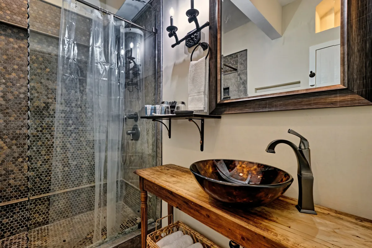 A modern, luxurious bathroom featuring a spacious walk-in shower, a stylish vanity with a bowl sink, a large mirror, and elegant sconce lighting. The ambiance is relaxing and rejuvenating.